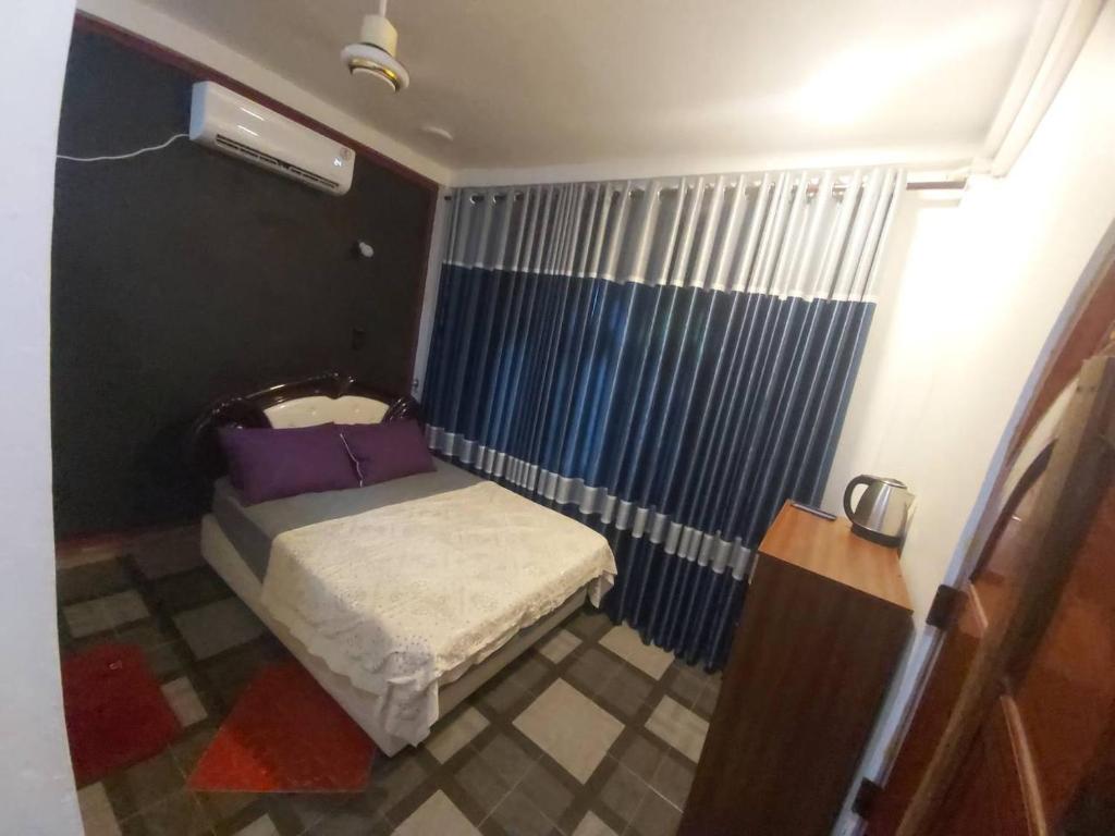 a small bedroom with a bed and a shower at Gabriel Lanka Hotel (PVT) LTD in Jaffna