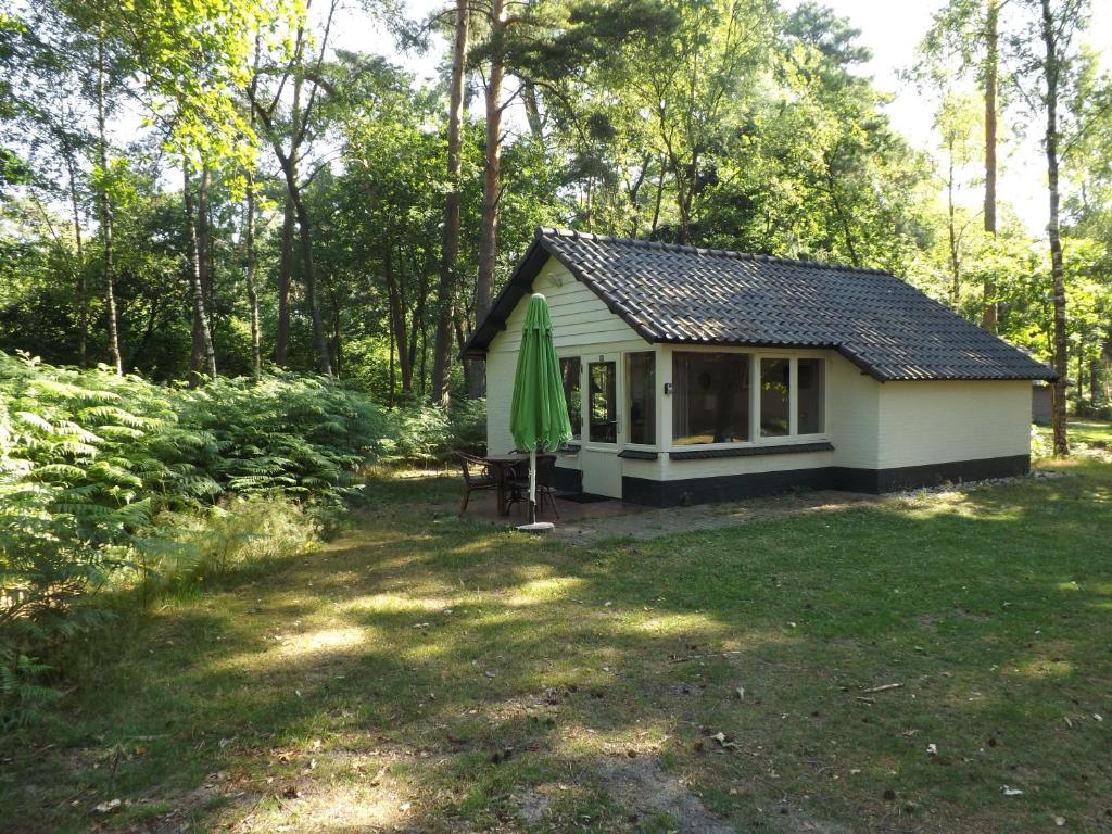 ein kleines Haus mit grünem Regenschirm im Hof in der Unterkunft Vosseven 27 Heksenkring in Stramproy