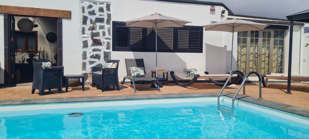 een zwembad met stoelen, tafels en parasols bij Beautiful Boho Glam Villa With Private Pool in Playa Blanca