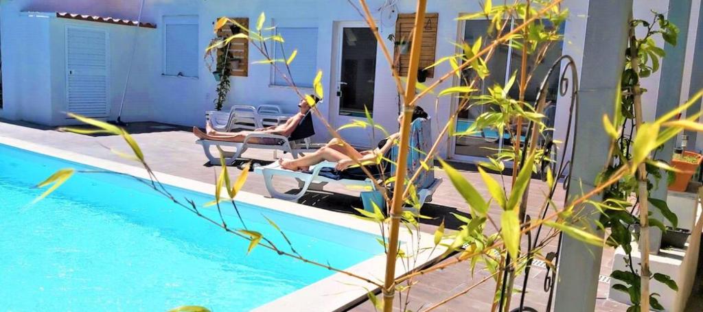 two women sitting in chairs next to a swimming pool at Seixal Bay Village - Estúdio Vista Piscina in Seixal