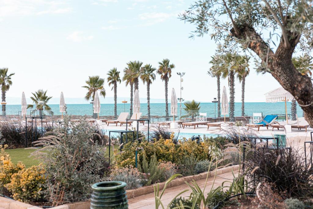 ein Resort mit einem Pool, Palmen und dem Meer in der Unterkunft Valerio Resort beach club in Margherita di Savoia