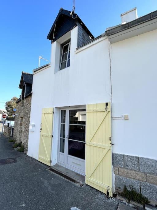 un bâtiment blanc avec un garage aux portes jaunes dans l'établissement Charmante Petite maisonnette, à Quiberon