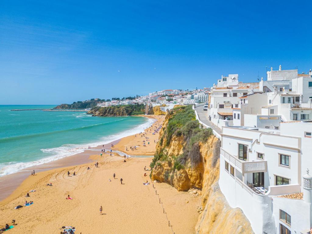 a view of a beach with people on the sand at Casa na Muralha - Beach front - Rooftop Jacuzzi by DreamvillasAlbufeira in Albufeira