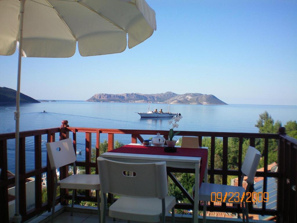 a balcony with a table and a boat in the water at Antiphellos Pension Küçükçakıl in Kas