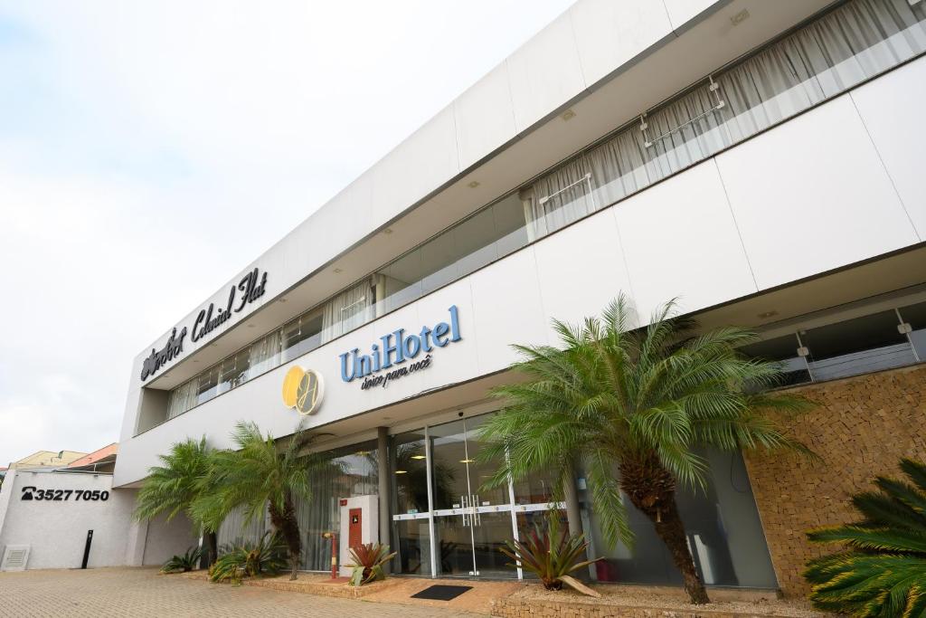 a store front of a building with palm trees in front at Colonial Flat Hotel in Itapetininga