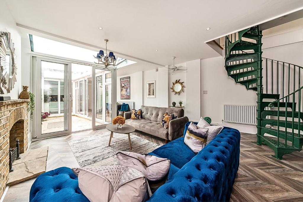 a living room with a blue couch and a staircase at The Secret KENSINGTON Garden Mews-2 Bedroom FULL HOUSE-2 Train Lines- SPACIOUS-Kings Road- Harrods -Chelsea Stadium-PRIVATE small patio in London