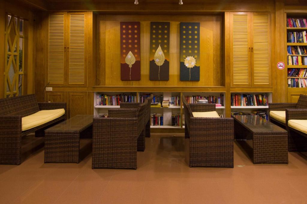 a library with wicker chairs and book shelves with books at Garden Home Kata in Kata Beach