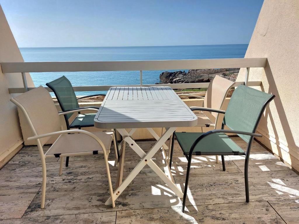 una mesa y sillas en un balcón con vistas al océano en STUDIO 1ERE LIGNE MER AVEC PKG QUARTIER CORNICHE, en Sète