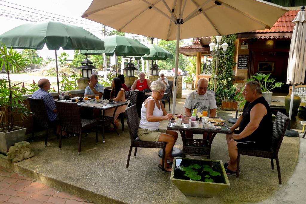a group of people sitting at tables in a restaurant at Garden Home Kata in Kata Beach