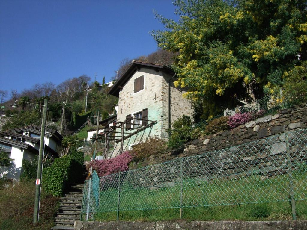 ein Steinhaus auf einem Hügel mit einem Zaun in der Unterkunft Rustico Storelli in Brissago