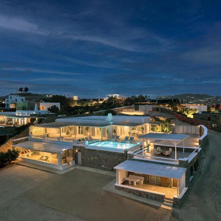 a large house with a swimming pool at night at Stunning 7-Bed Villa Villa Panamera in Psarou