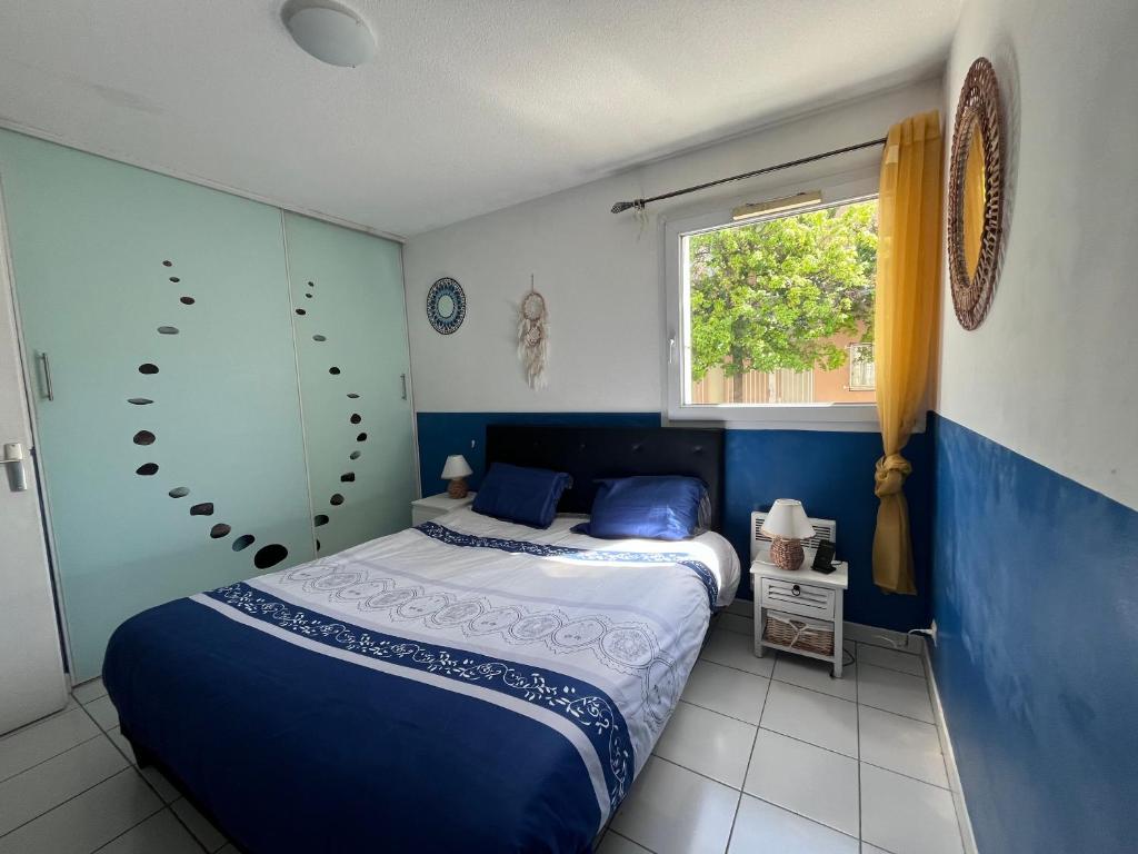 a blue and white bedroom with a bed and a window at Grand Appartement T2, charmant jardin in Montpellier