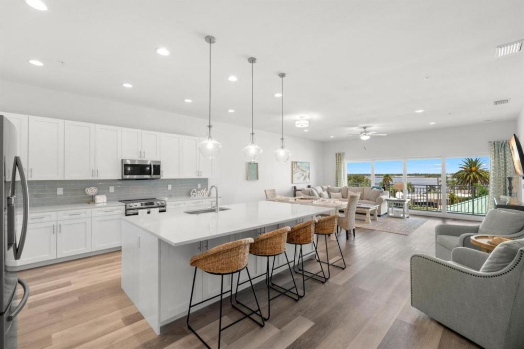 a kitchen and living room with white cabinets and a large island at Madeira Del Mar Penthouse #2- Premier in St. Pete Beach
