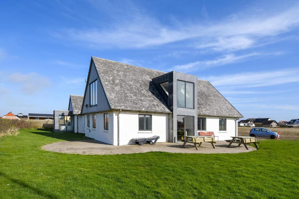 a white house with a black roof on a grass field at Pool house with beautiful view by the sea - SJ650 in Lemvig
