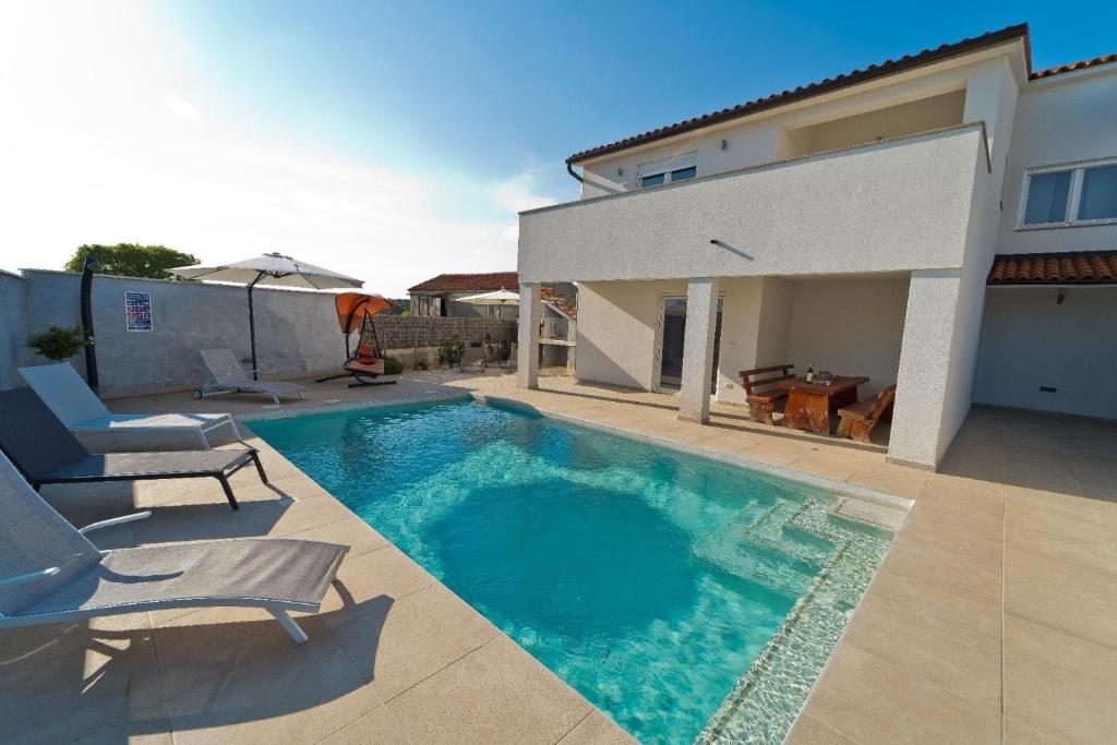 einen Pool mit zwei Stühlen und ein Haus in der Unterkunft Ferienhaus für 6 Personen und 2 Kinder in Pula, Istrien Istrische Riviera in Pula