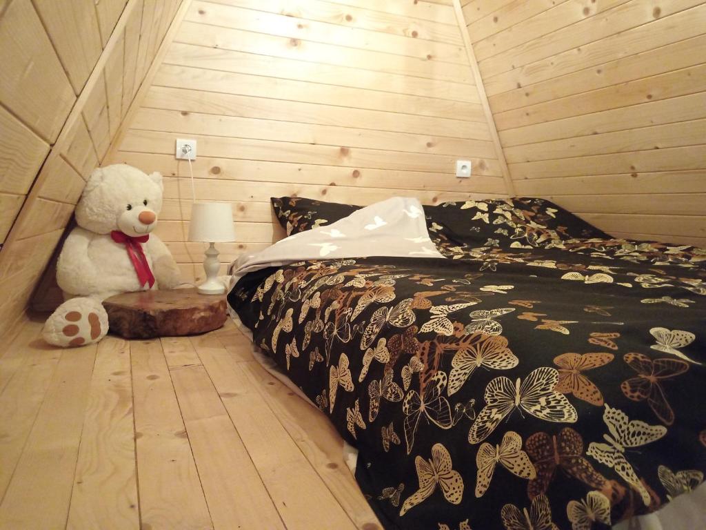 misia siedzącego obok łóżka w pokoju w obiekcie Vikendica "Koliba kraj puta" w mieście Divčibare