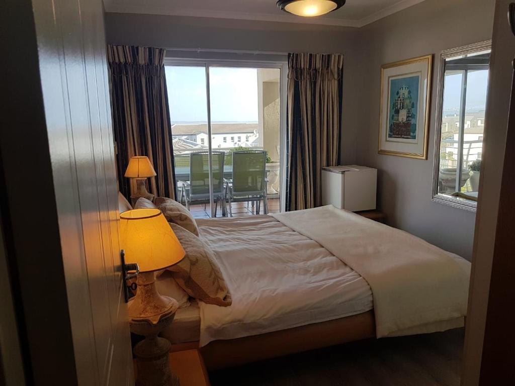 1 dormitorio con 1 cama con lámpara y ventana en Dolphin Ridge, en Ciudad del Cabo