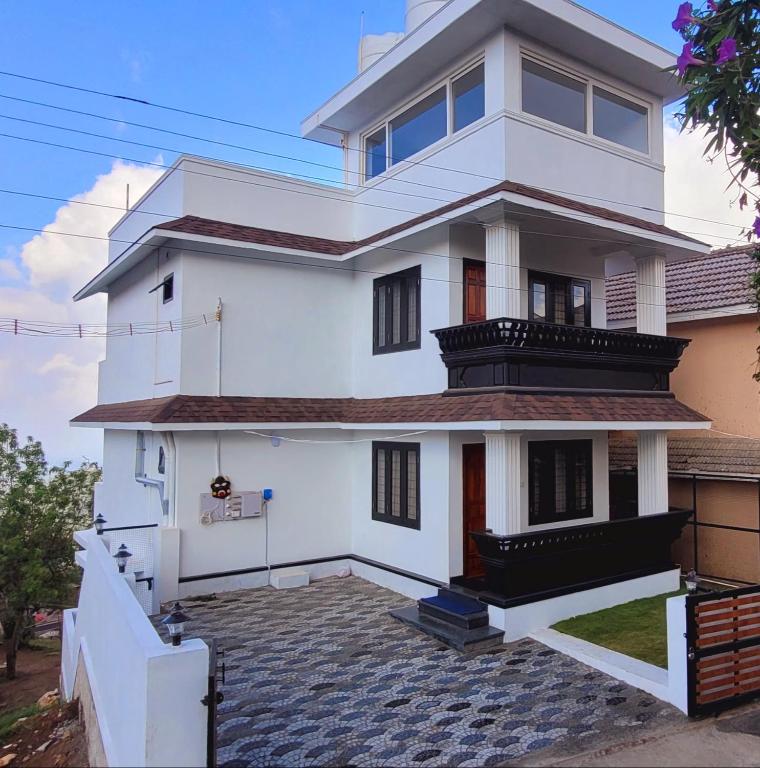 a white house with a large driveway in front of it at Sky High Villa Annex in Kodaikānāl