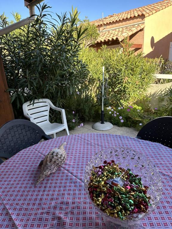 une table avec un bol de perles sur une nappe violette dans l'établissement HOLIDAYLAND 429 VILLA T2 MEZZANINE 6 couchages climatisé NARBONNE PLAGE, à Narbonne-Plage