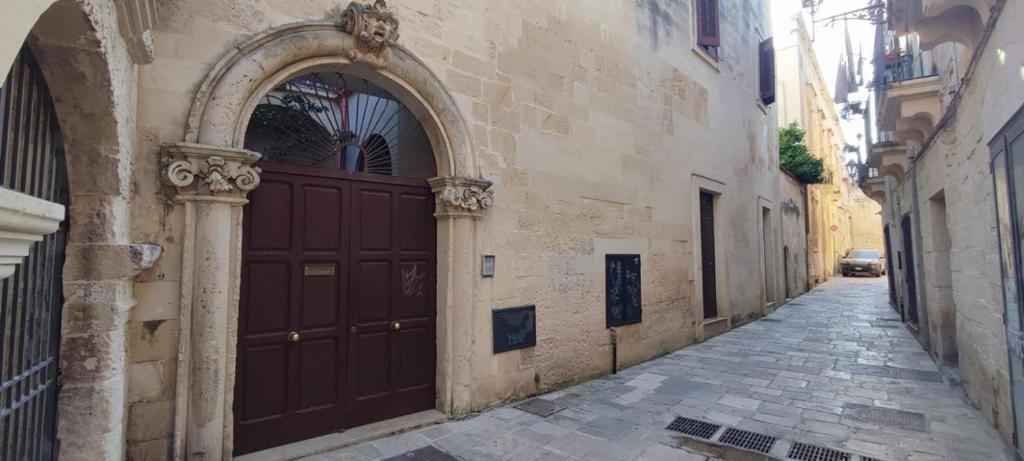 an alley with a large brown door on a building at Victoria Apt - Historical Centre Lecce in Lecce
