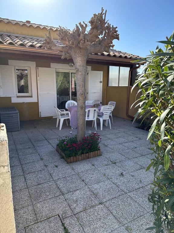 d'une terrasse avec une table, des chaises et un arbre. dans l'établissement HOLIDAYLAND 433 VILLA T2 MEZZANINE 6 couchages NARBONNE PLAGE, à Narbonne-Plage