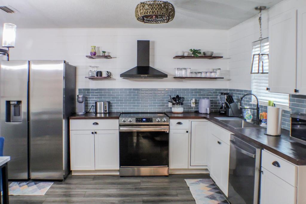 a kitchen with white cabinets and a stainless steel refrigerator at Fenced House Beach Walk Sleeps 16 near St Andrew Park - Schooners in Panama City Beach