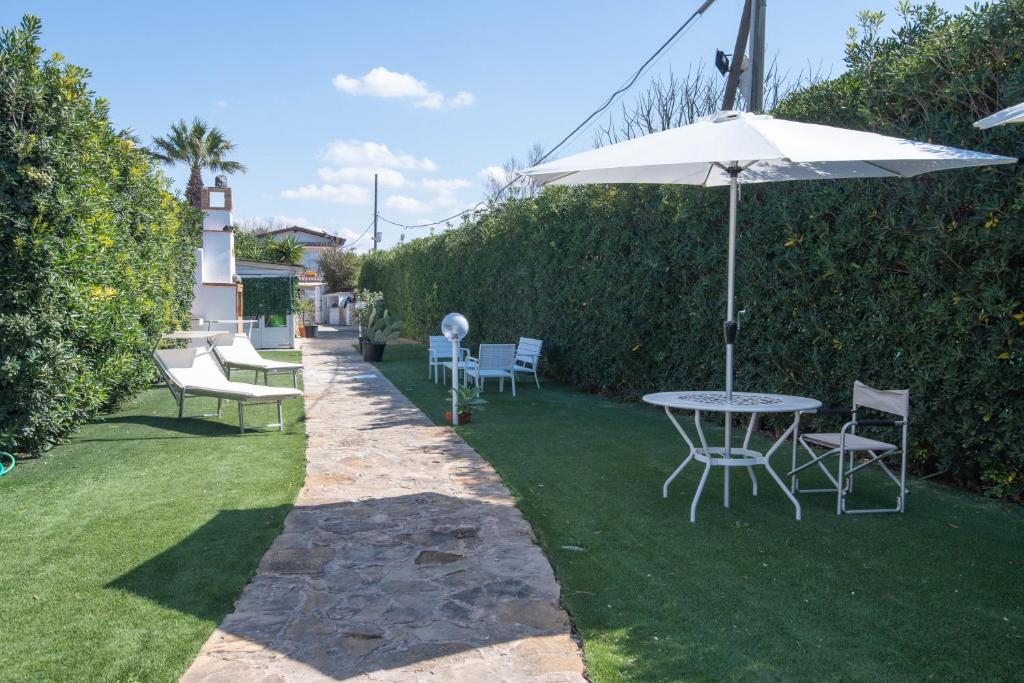 a table and chairs with an umbrella on a lawn at Villa Elpaix in Marsala