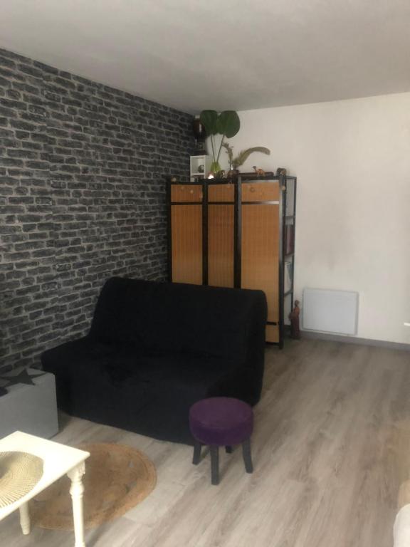- un salon avec un canapé noir et un tabouret pourpre dans l'établissement Appartement de la fontaine, à Bry-sur-Marne
