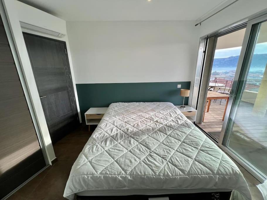 a bedroom with a bed and a balcony at Appartement Sole - vue golfe de Porto Vecchio in Porto-Vecchio
