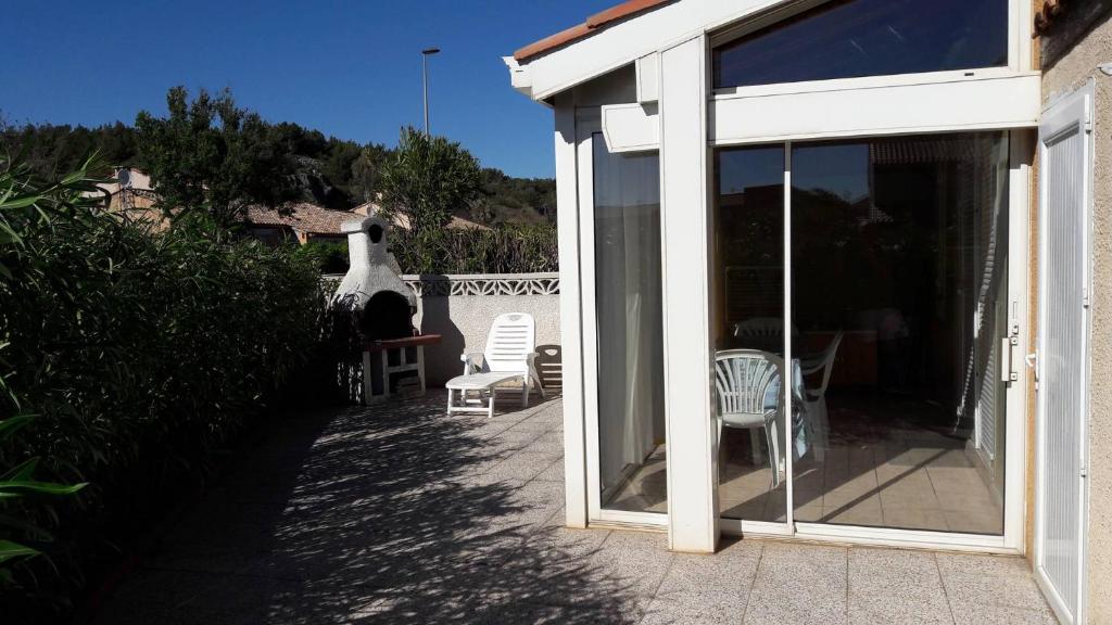 une maison avec un patio avec des chaises et une porte vitrée dans l'établissement HOLIDAYLAND 441 VILLA T2 MEZZANINE 6 couchages avec véranda NARBONNE PLAGE, à Narbonne-Plage