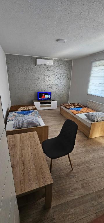 um quarto com duas camas, uma mesa e uma cadeira em Apartmani Roki em Tuzla