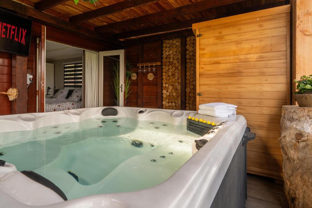 une baignoire jacuzzi dans une chambre avec un mur en bois dans l'établissement Drents Genieten - Lavendelheide met uitzicht op het water, à Erm