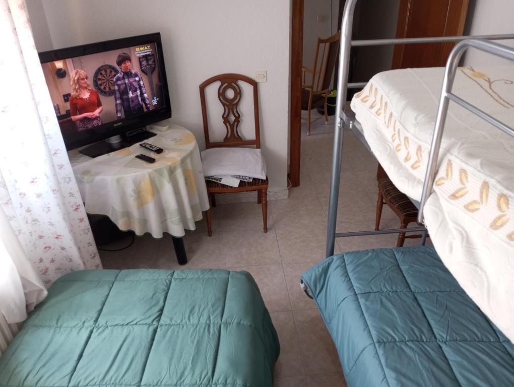 a bedroom with a bunk bed and a table with a tv at Habitacion Privada Triple Toledo in Toledo