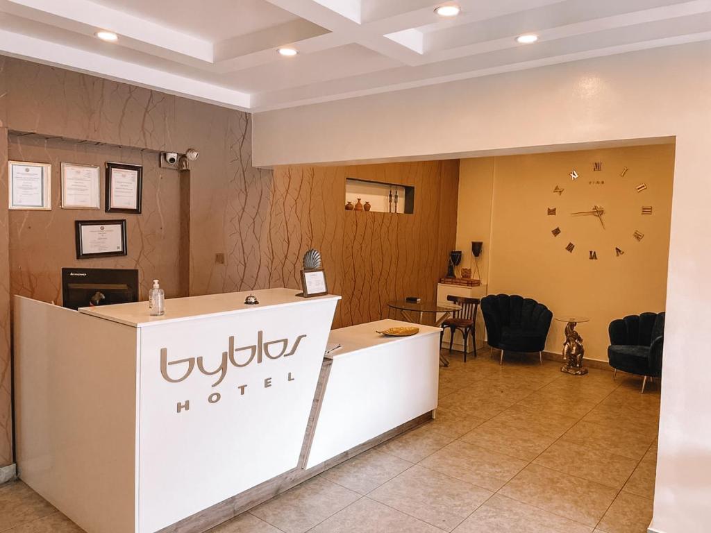 a lobby with a counter and a clock on the wall at Sky Suites Osu in Accra