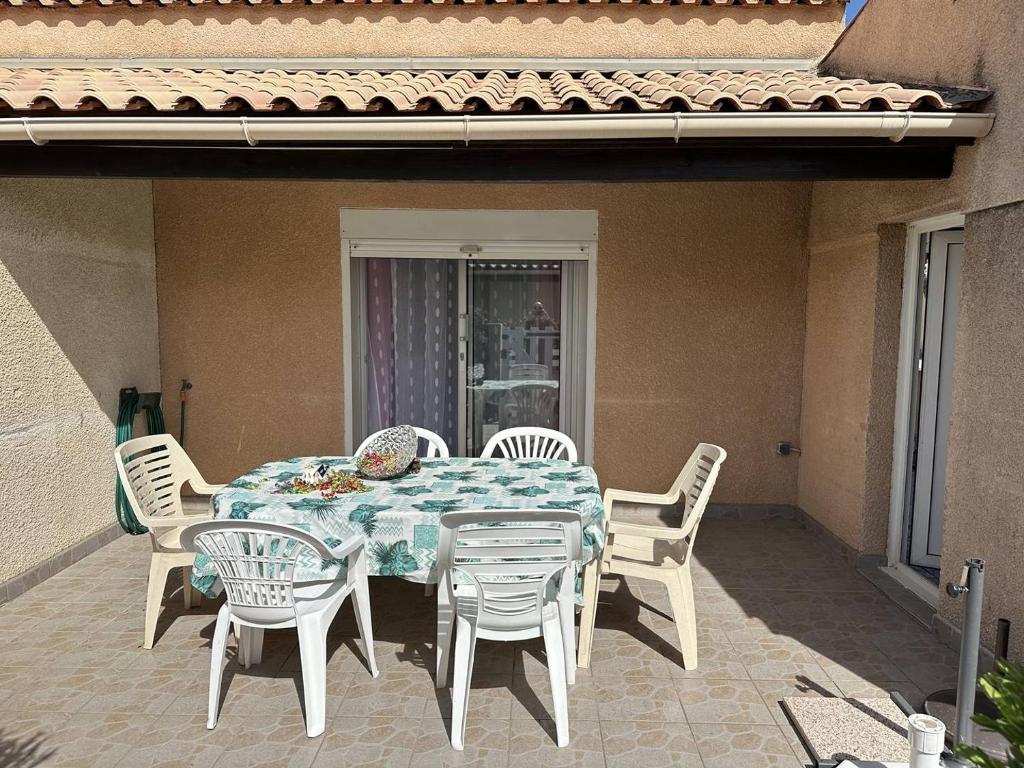 une table et des chaises assises sur une terrasse dans l'établissement HOLIDAYLAND 122 VILLA T3 MEZZANINE 7 couchages climatisé NARBONNE PLAGE, à Narbonne-Plage