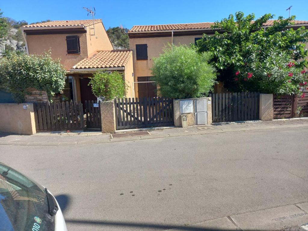 une maison avec une clôture en face d'une rue dans l'établissement HOLIDAYLAND CALAMAR PAVILLON T2 6 couchages climatisé Narbonne Plage, à Narbonne-Plage