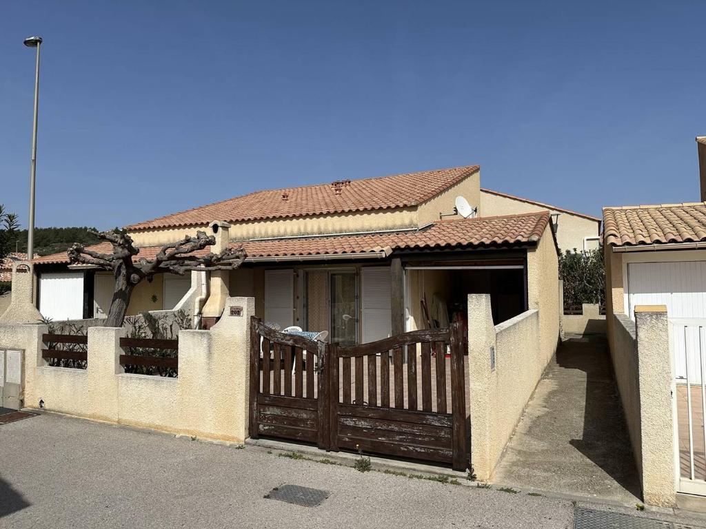 une maison avec une porte en bois et une clôture dans l'établissement HOLIDAYLAND 202 VILLA T3 MEZZANINE 6 couchages NARBONNE PLAGE, à Narbonne-Plage