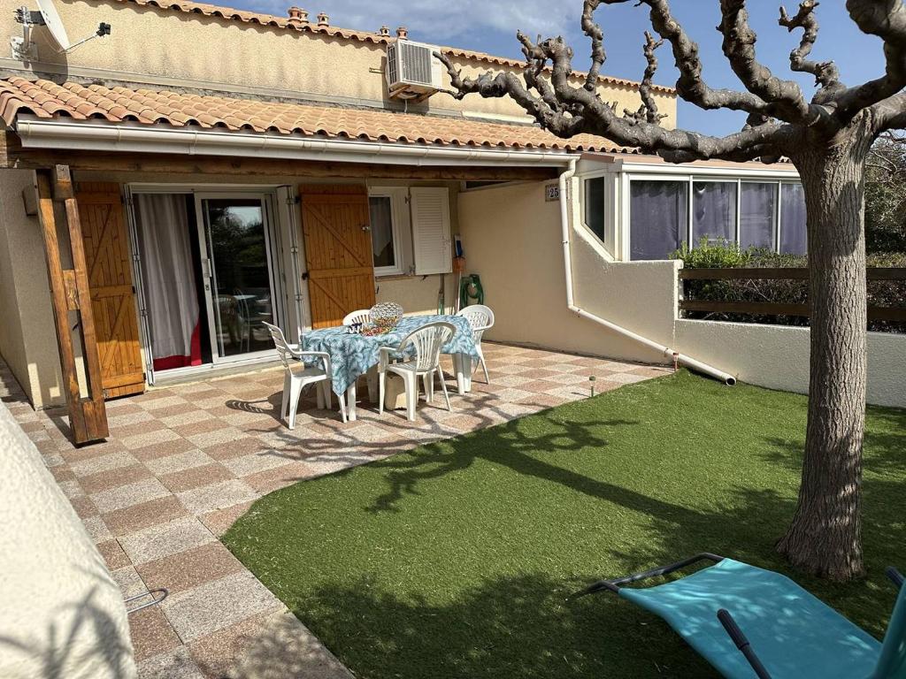 d'une terrasse avec une table, des chaises et un arbre. dans l'établissement HOLIDAYLAND 256 VILLA T2 MEZZANINE 6 couchages climatisé NARBONNE PLAGE, à Narbonne-Plage