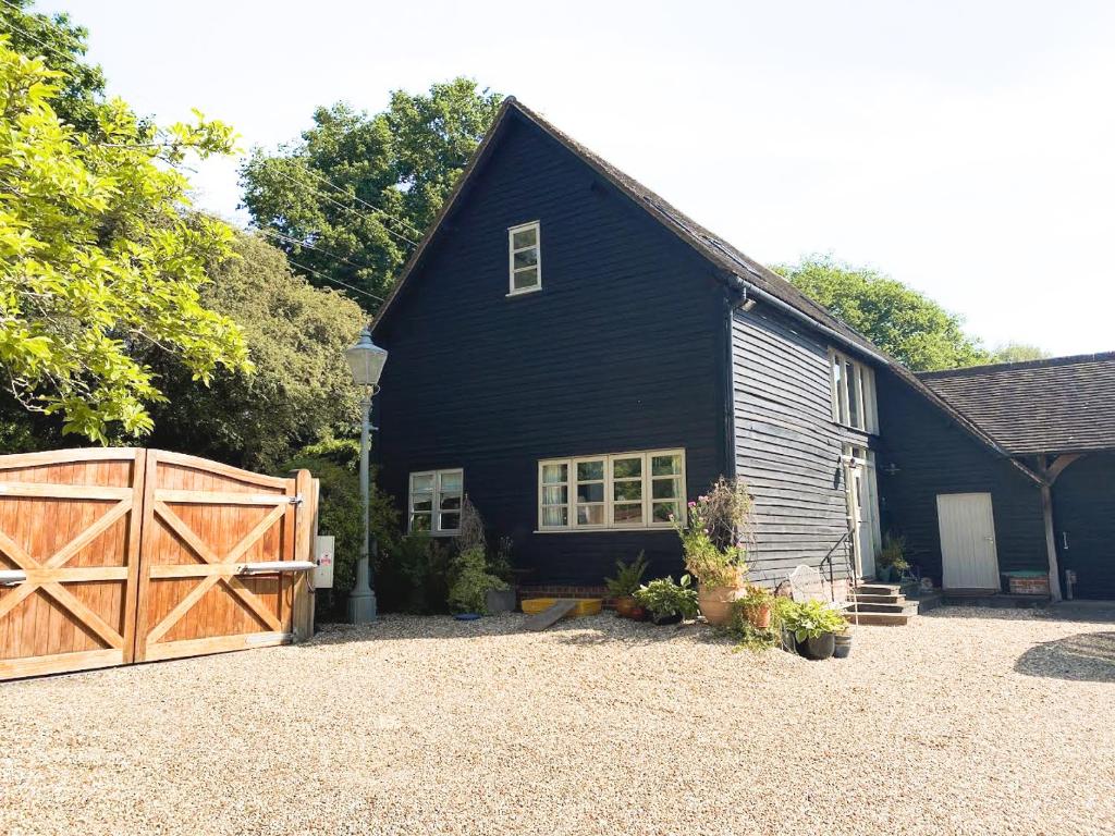 a black house with a barn with a wooden gate at The Barn at Stoaches by Huluki in Haywards Heath