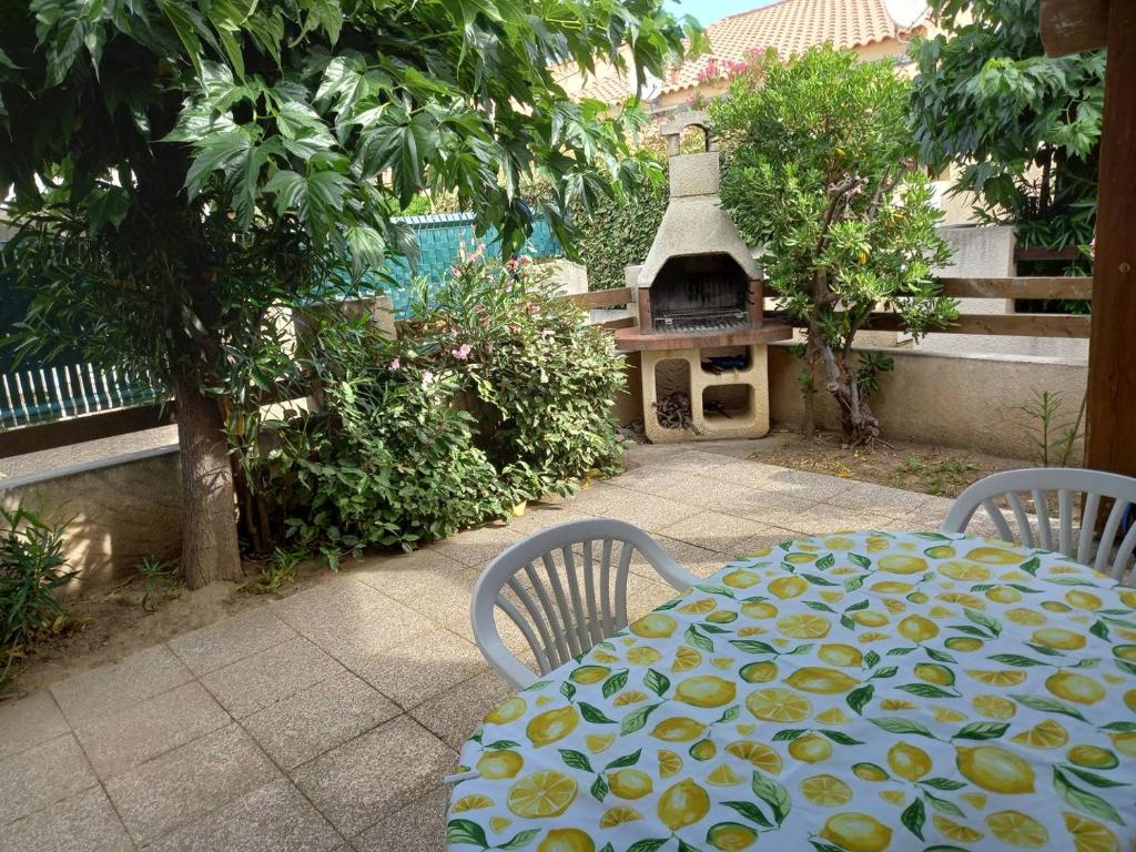 - une table et des chaises avec un four à pizza dans l'arrière-cour dans l'établissement HOLIDAYLAND 212 VILLA T2 MEZZANINE 6 couchages climatisé NARBONNE PLAGE, à Narbonne-Plage
