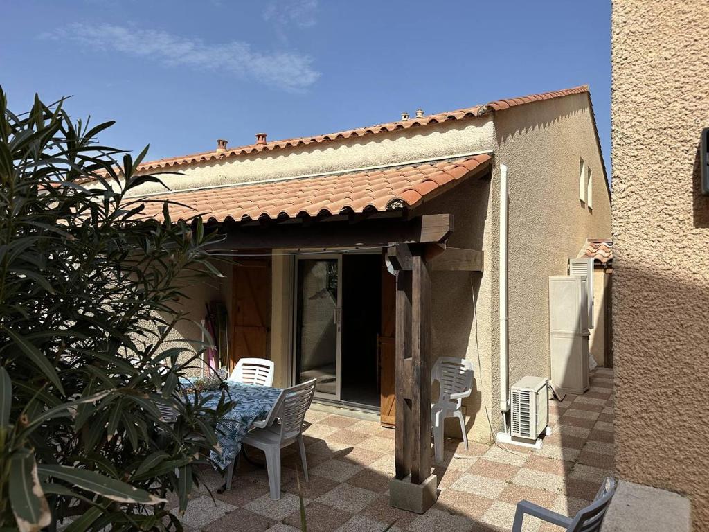 un patio avec une table et des chaises devant une maison dans l'établissement HOLIDAYLAND 224 VILLA T2 MEZZANINE 7 couchages climatisé NARBONNE PLAGE, à Narbonne-Plage