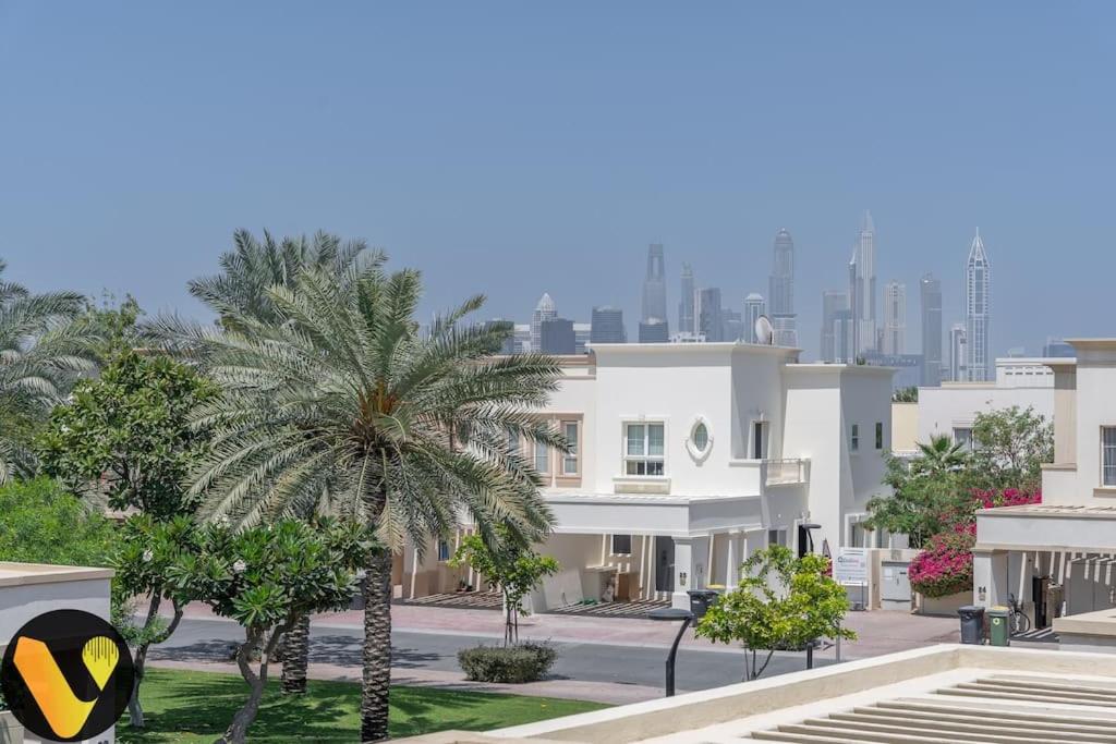 a building with a palm tree in front of a city at Vogue Villa Near Golf/Ski Dubai/ Ibn Battuta Mall in Dubai