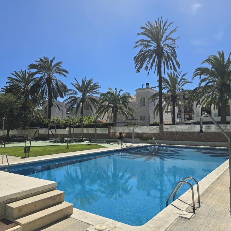 a swimming pool with palm trees in the background at Els Terrers Sun Flat in Benicàssim