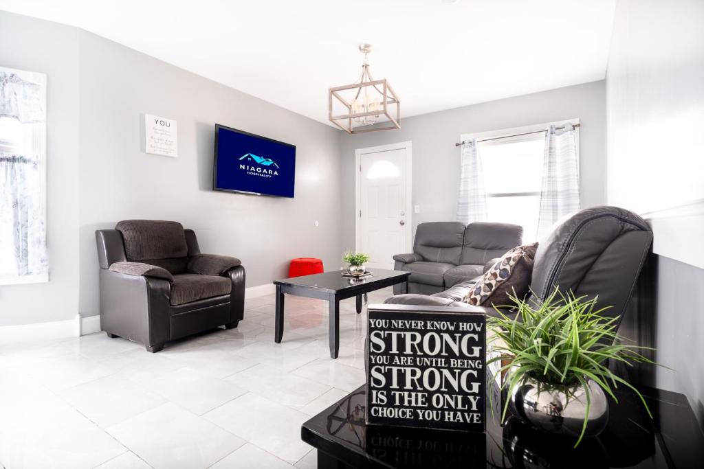 a living room with two chairs and a couch at The Maid of the Mist Villa- With Private Yard & Parking, Minutes From Falls & Casino by Niagara Hospitality in Niagara Falls