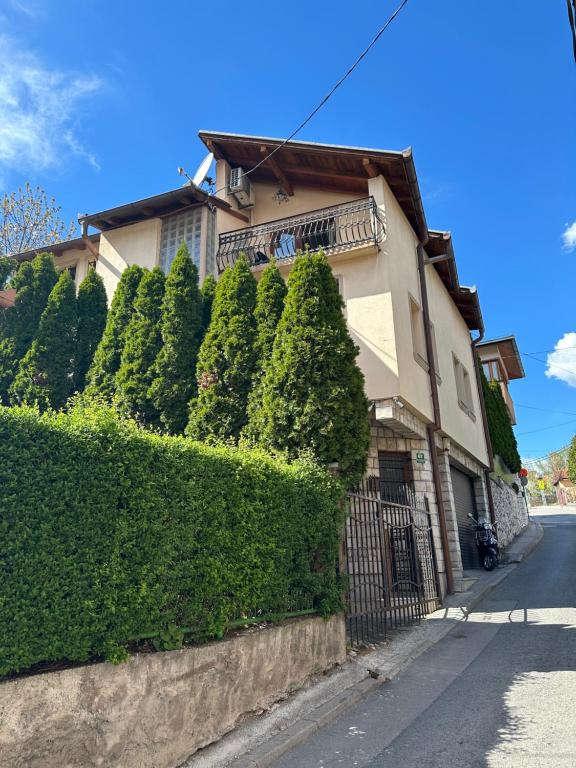 una casa con una siepe di fronte a un edificio di One Love a Sarajevo