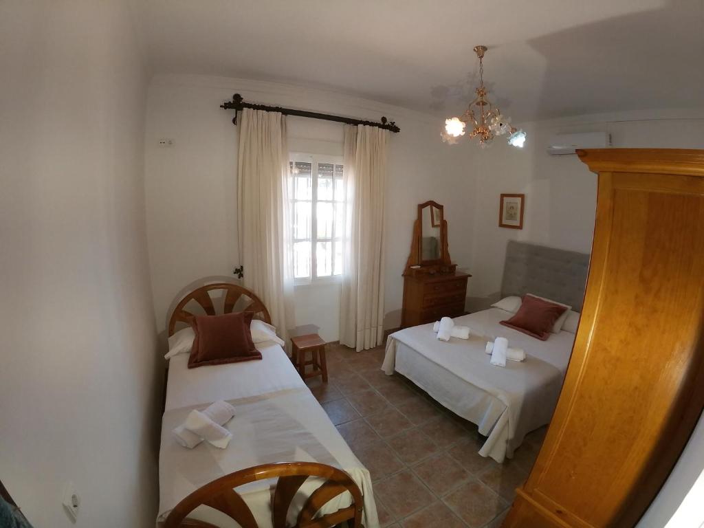 Un dormitorio con dos camas y una ventana. en Casa Maleda, en Hornachuelos