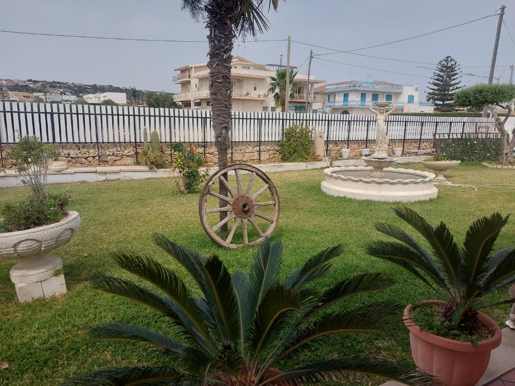 um jardim com uma roda de carroça num quintal em A casa di Franco em Marina di Ragusa