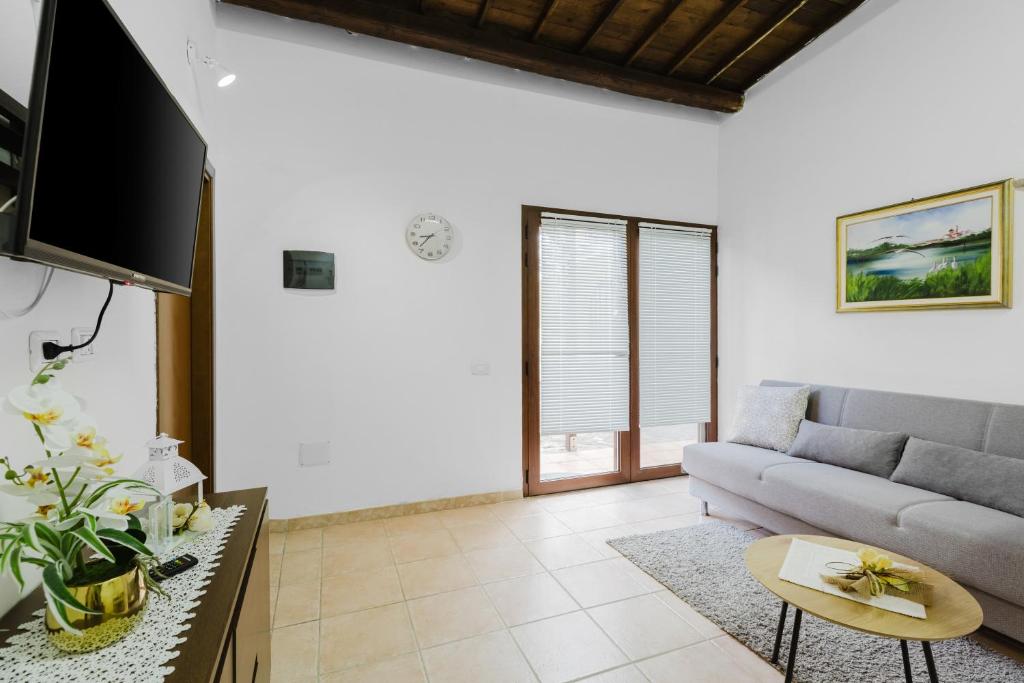 a living room with a couch and a tv at Il Corbezzolo Apartment in Palmas Arborea