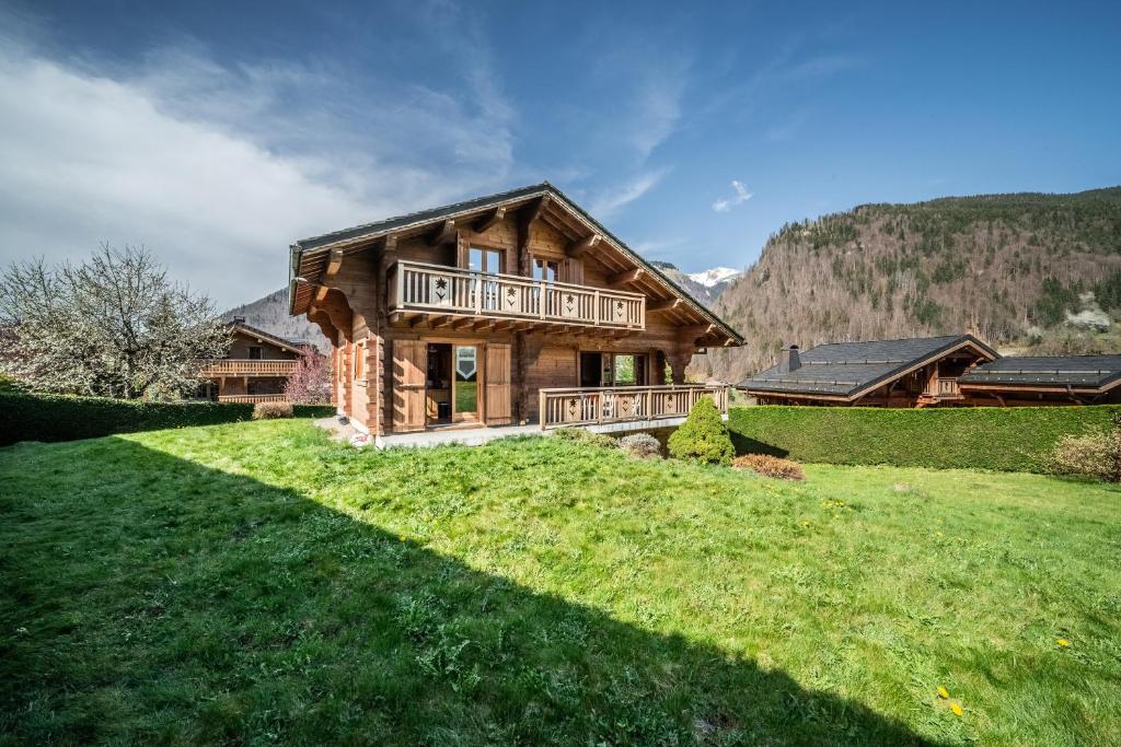 a log house with a large lawn in front of it at Chalet L'arba clar - 4 étoiles in Morzine