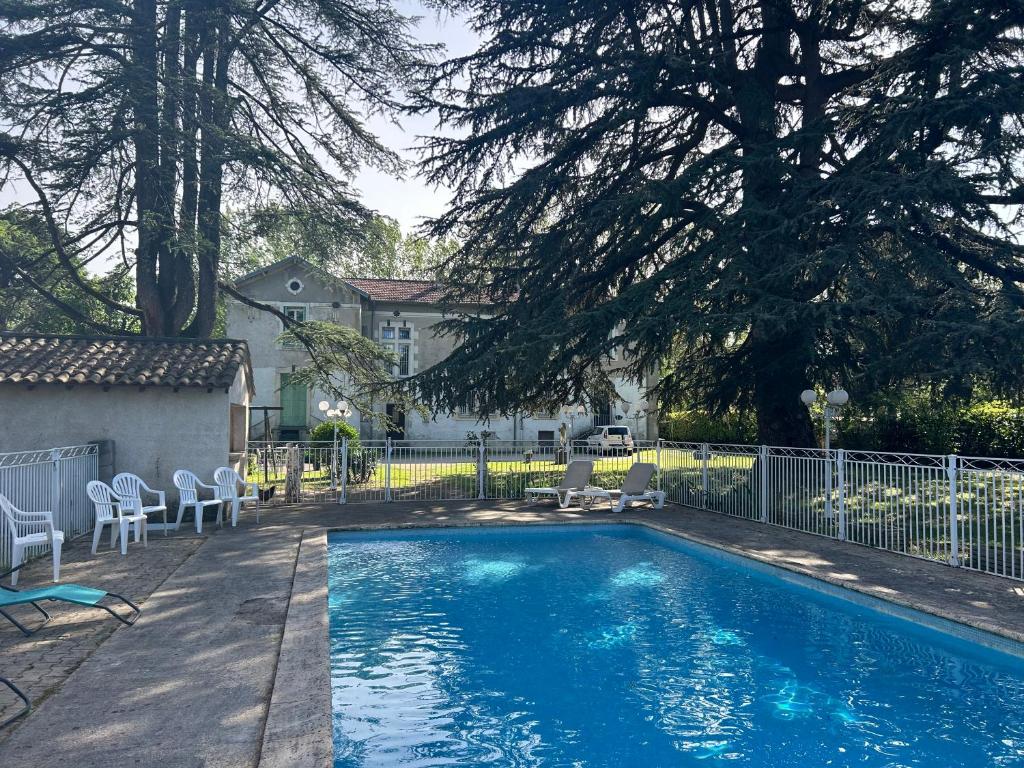 a swimming pool with chairs and a fence at Le Parc aux Cedres in Laroque